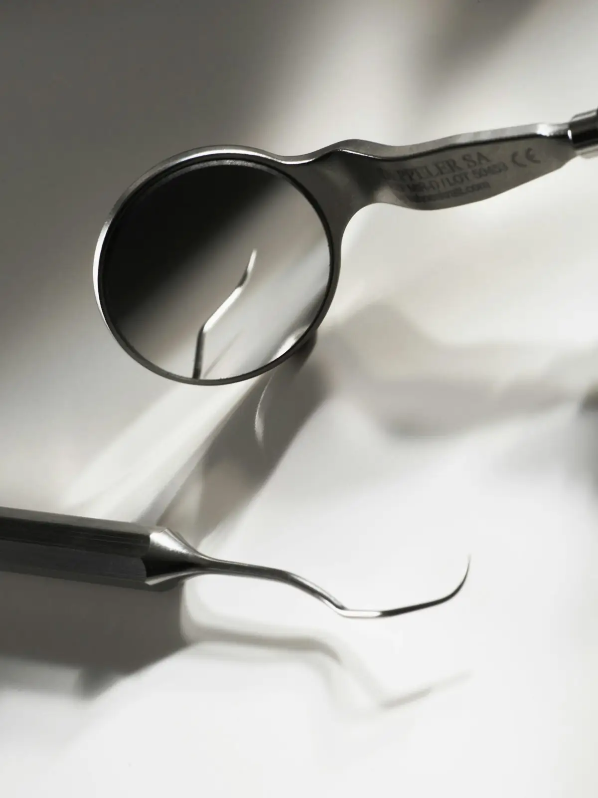 Espejo y sonda dental sobre una superficie blanca