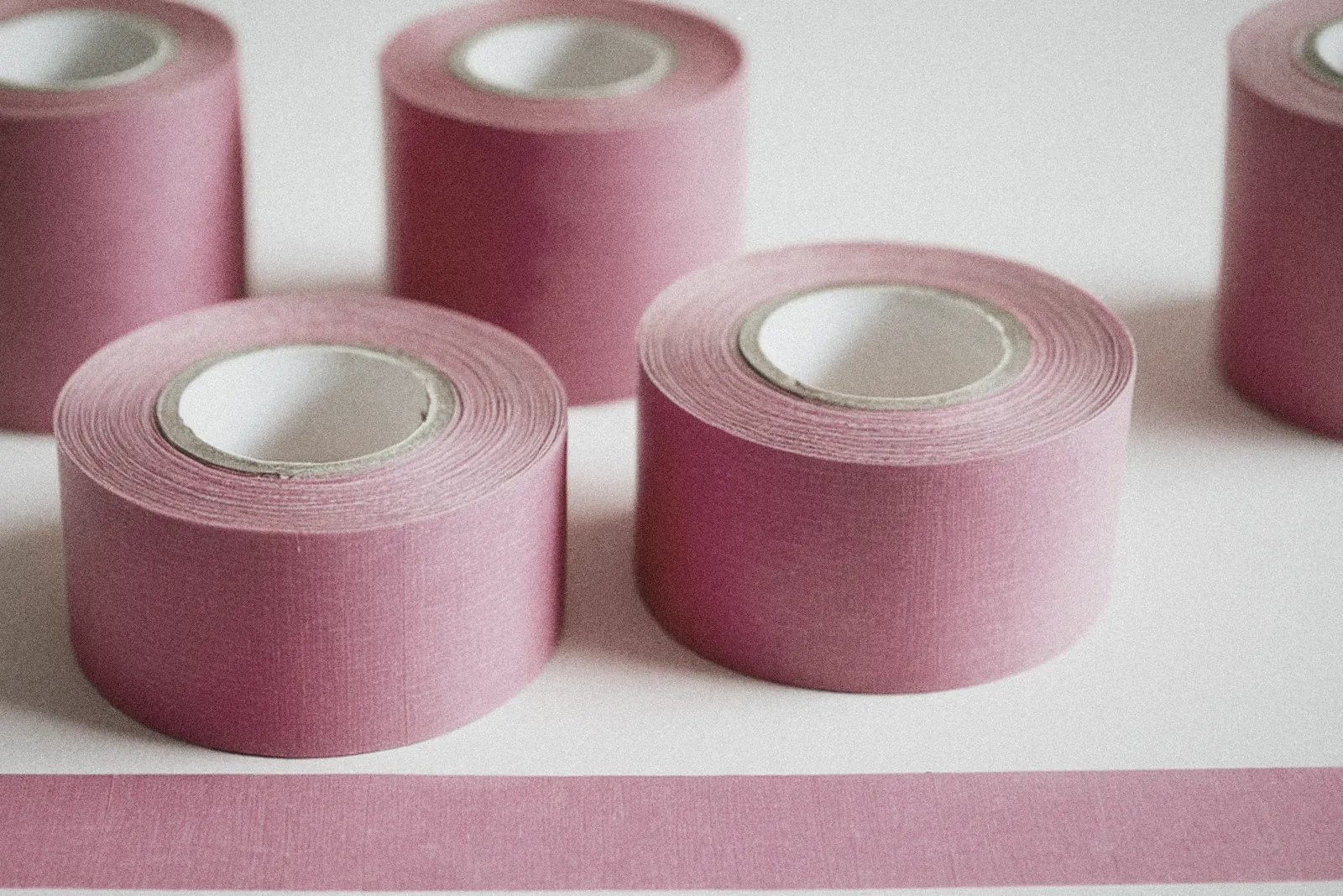 Rollos de cinta de kinesiología rosa sobre una mesa blanca