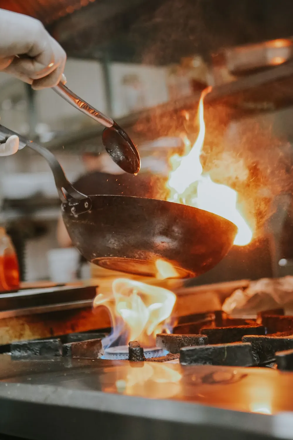 Un cocinero salteando en un wok con llama
