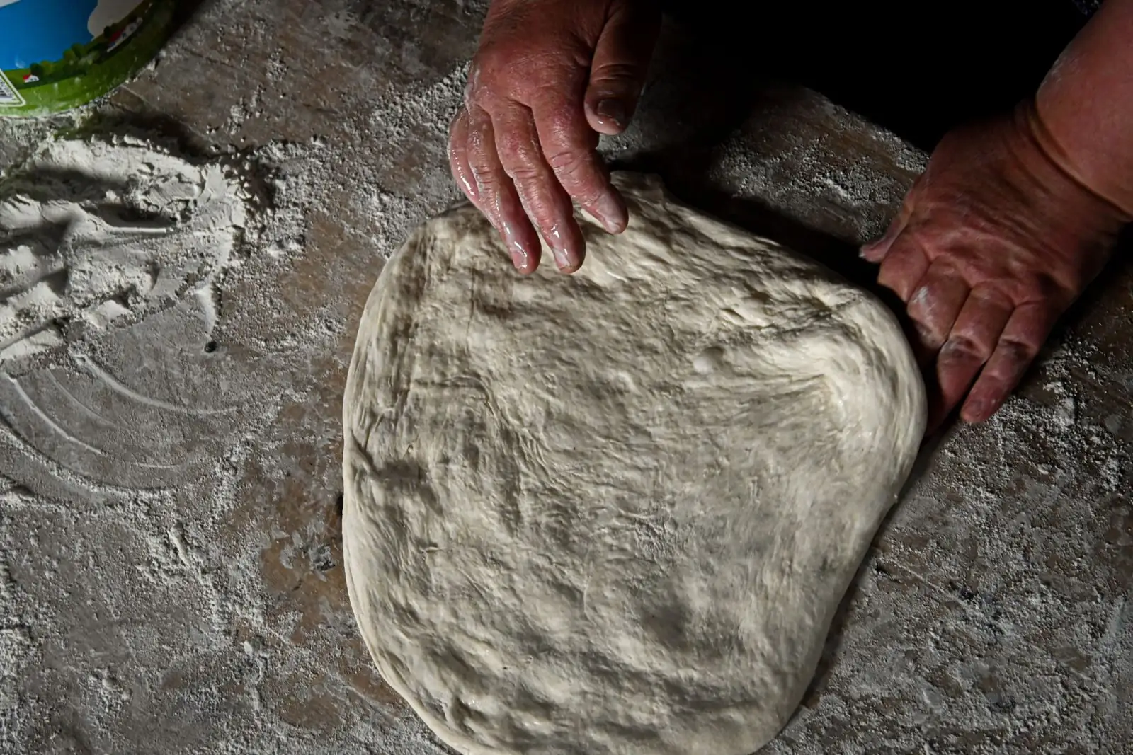 Manos amasando una masa sobre una mesa enharinada
